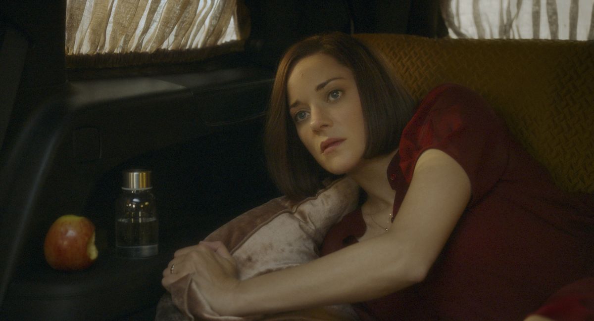 Marion Cotillard lying in the back seat of a car, just awakened from a nightmare.